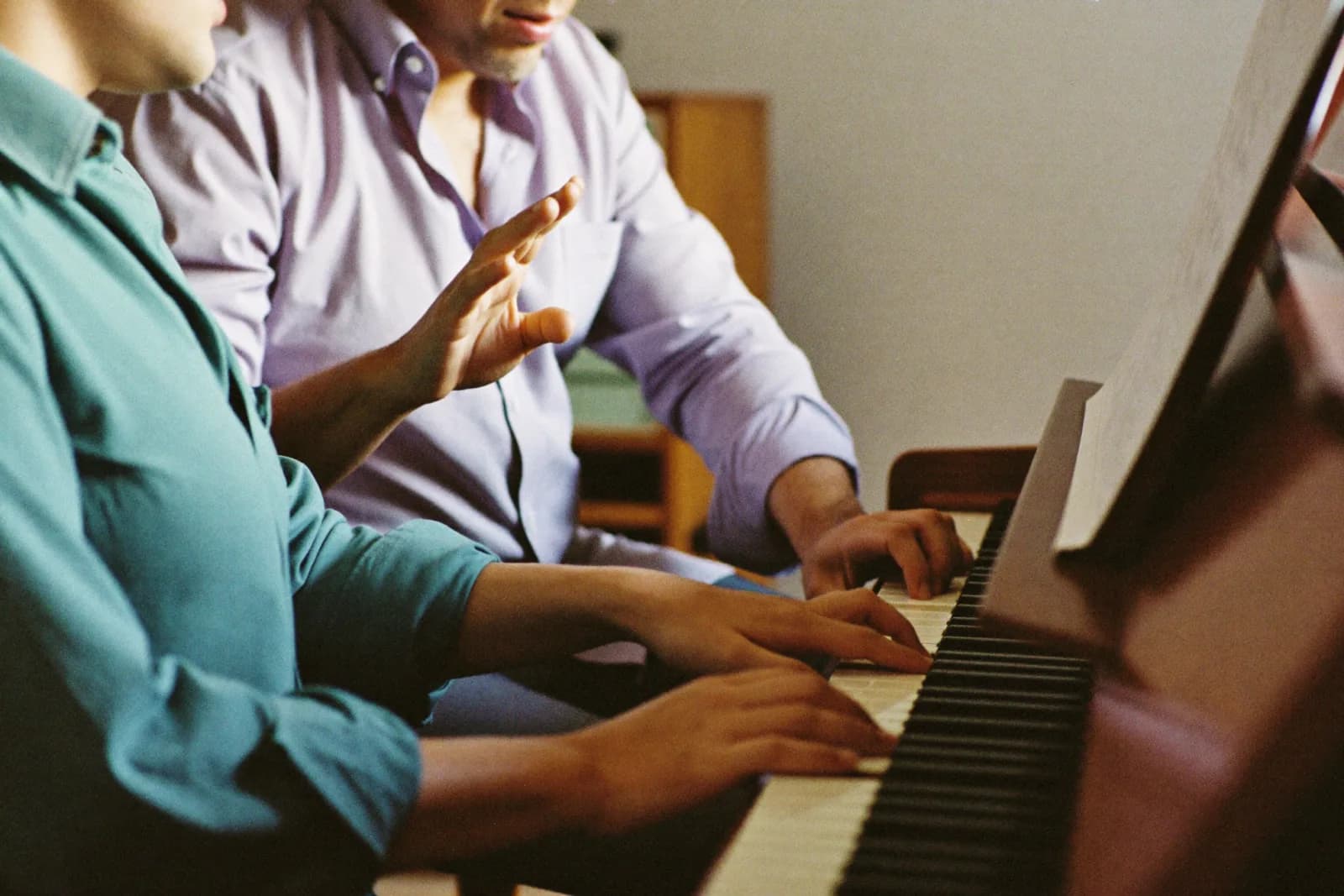 Escena ficticia generada de una clase de piano entre dos personas adultas.